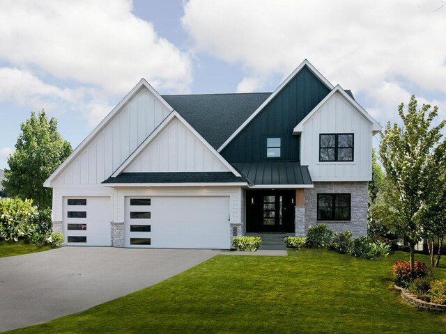 modern inspired farmhouse with a garage, stone siding, concrete driveway, a front lawn, and board and batten siding