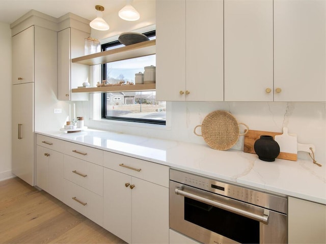 kitchen featuring tasteful backsplash, light wood-style flooring, oven, white cabinetry, and open shelves