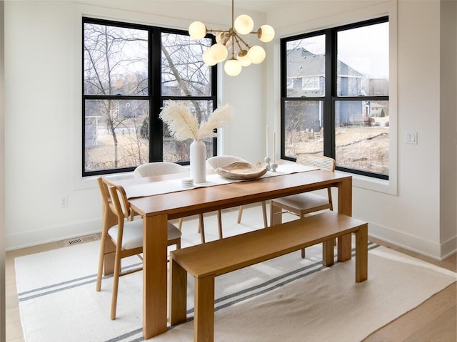 dining space with a chandelier, visible vents, and baseboards