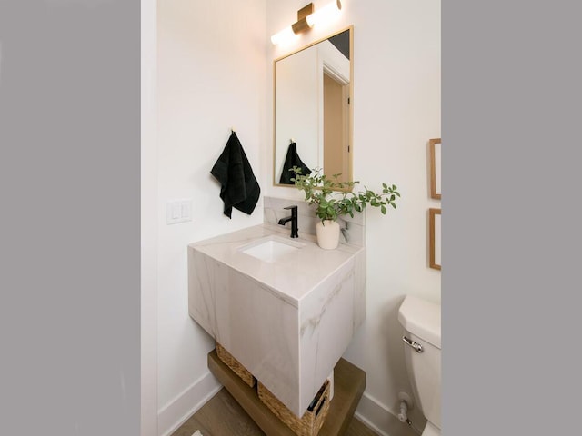 bathroom featuring toilet, baseboards, and vanity