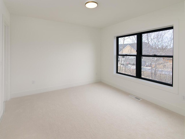 unfurnished room featuring baseboards, visible vents, and light colored carpet