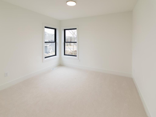 spare room featuring light carpet, visible vents, and baseboards