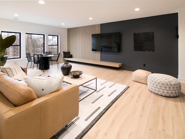 living room with an accent wall, baseboards, wood finished floors, and recessed lighting