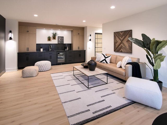 living room with recessed lighting, beverage cooler, light wood-style floors, baseboards, and wet bar