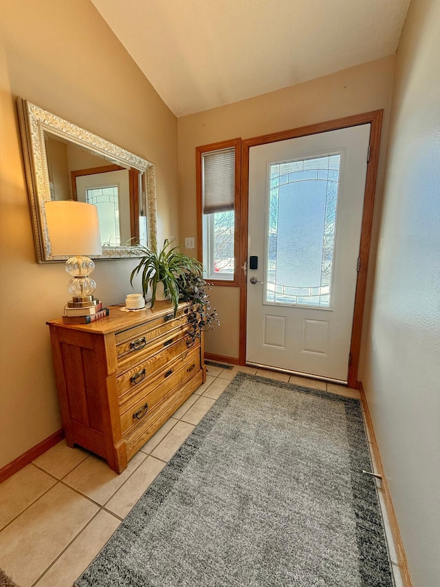 entryway with light tile patterned floors, lofted ceiling, and baseboards