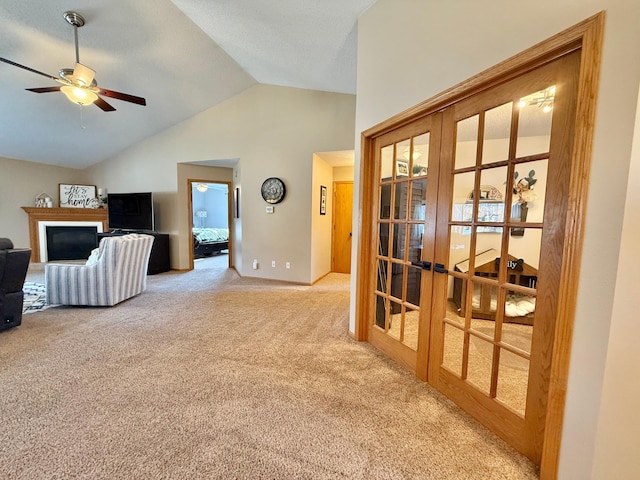 unfurnished living room featuring french doors, carpet, lofted ceiling, a glass covered fireplace, and ceiling fan