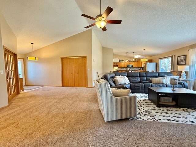 living area featuring lofted ceiling, light colored carpet, ceiling fan, and a textured ceiling