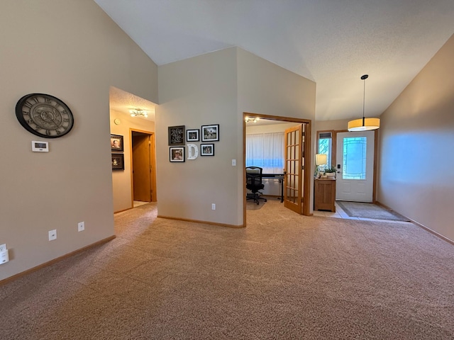 foyer with high vaulted ceiling, light carpet, and baseboards