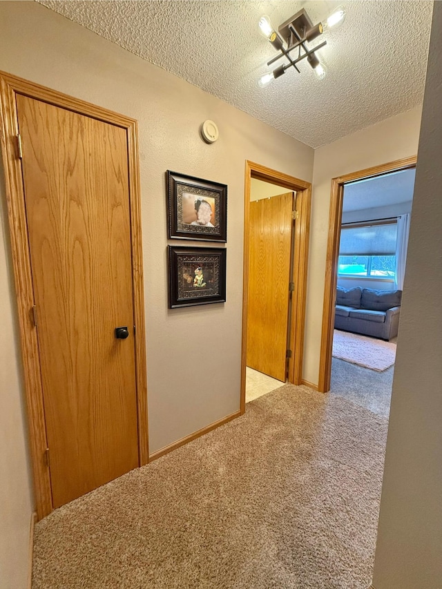 corridor featuring a textured ceiling and carpet