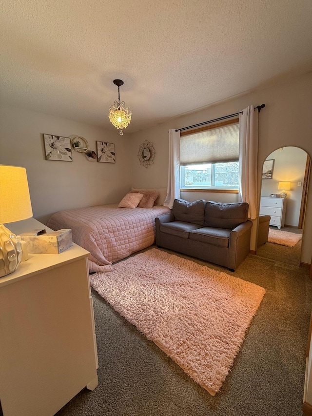 carpeted bedroom with arched walkways and a textured ceiling