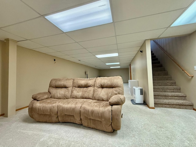 living room featuring carpet floors, stairs, a paneled ceiling, and baseboards