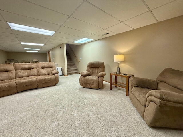 carpeted living area with a paneled ceiling and stairs