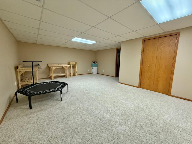 workout room featuring a paneled ceiling, carpet, and baseboards
