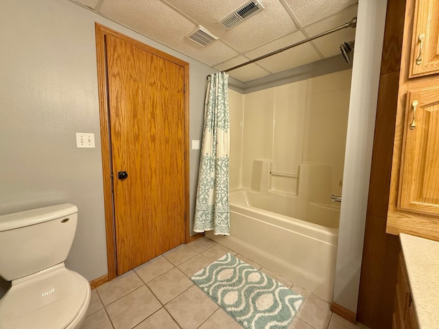 bathroom with a paneled ceiling, toilet, shower / tub combo with curtain, and tile patterned floors