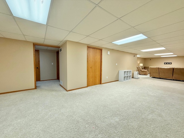 finished basement with carpet floors, a paneled ceiling, and baseboards