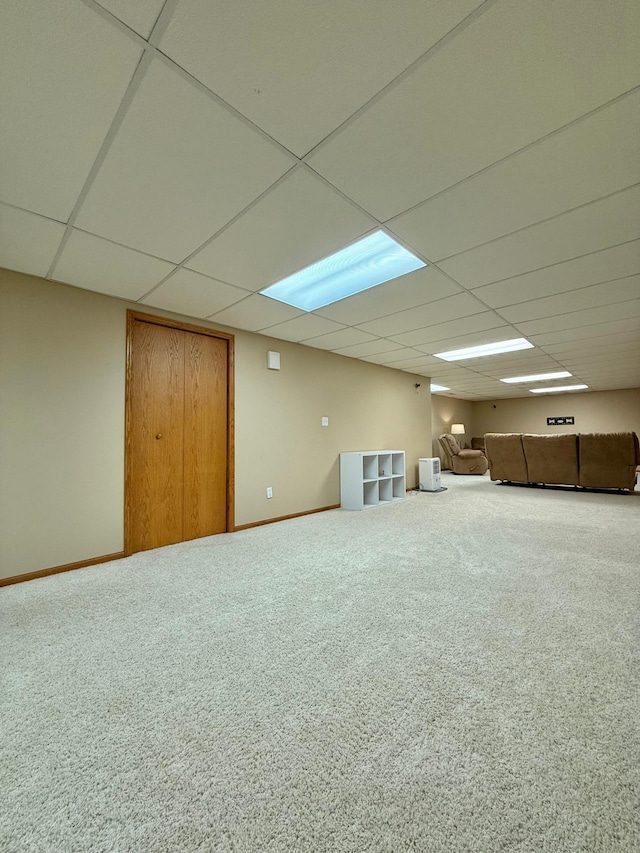 finished basement featuring a drop ceiling, carpet flooring, and baseboards