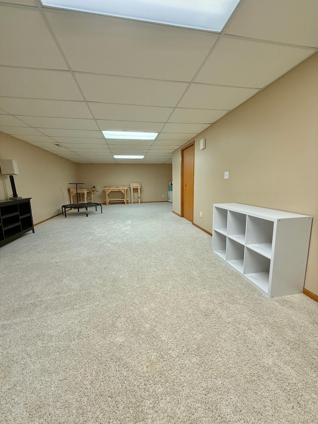 unfurnished room featuring a paneled ceiling, carpet flooring, and baseboards
