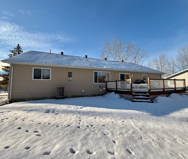 snow covered back of property with a wooden deck and central AC unit
