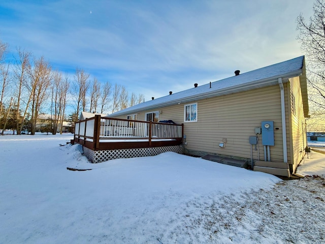 snow covered rear of property with a deck
