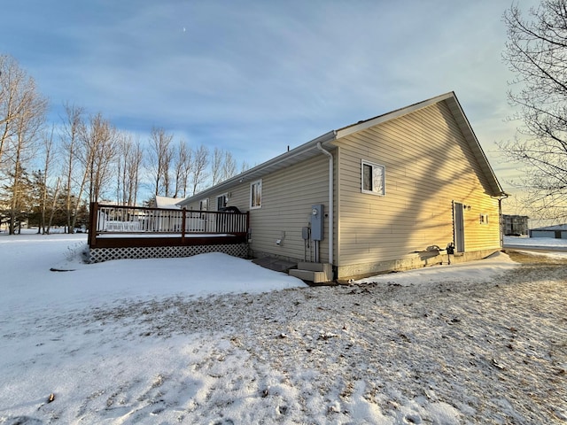 snow covered back of property featuring a wooden deck