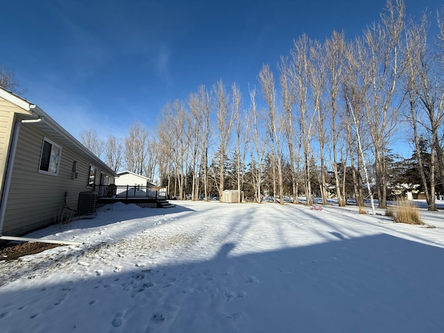 snowy yard featuring a deck and central air condition unit
