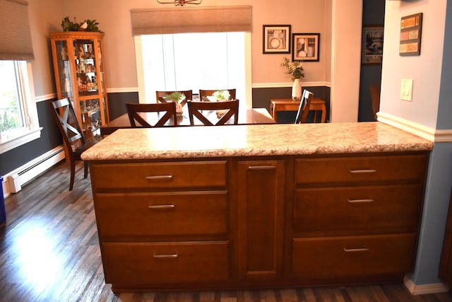 kitchen featuring dark hardwood / wood-style flooring, a baseboard radiator, and light stone counters