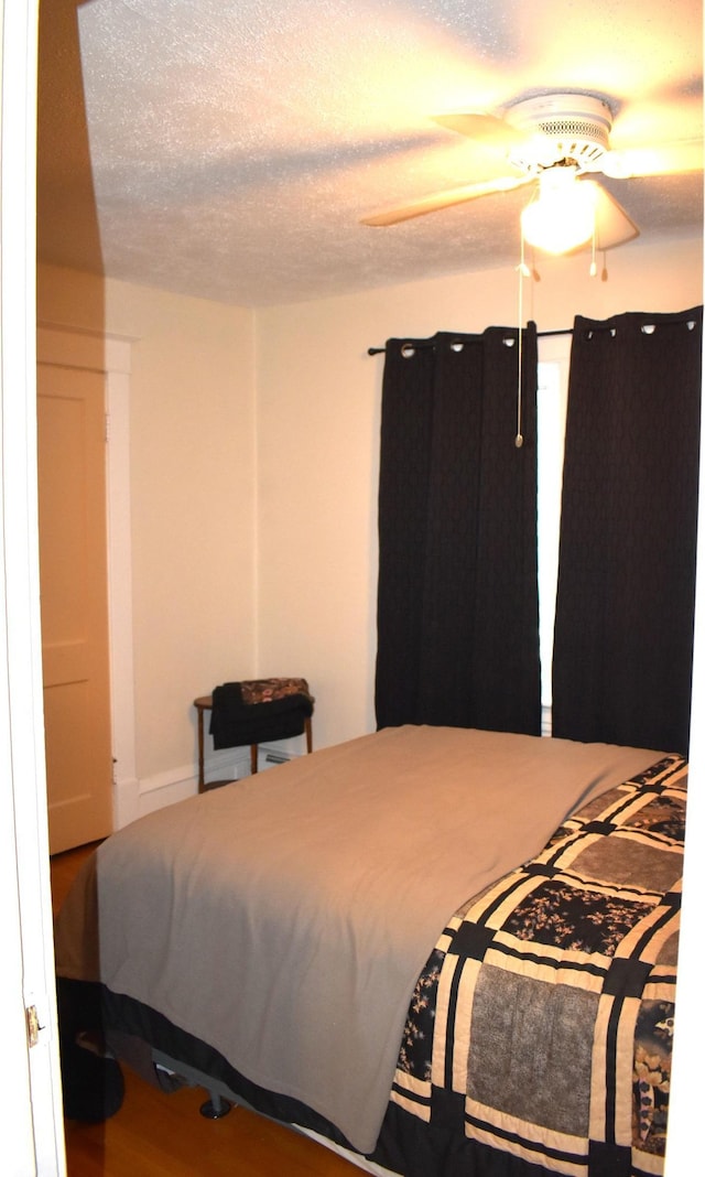 bedroom with a textured ceiling, hardwood / wood-style flooring, and ceiling fan