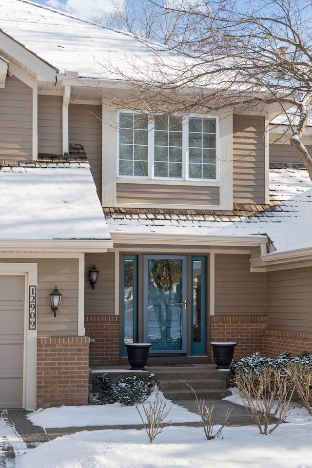 snow covered property entrance with a garage