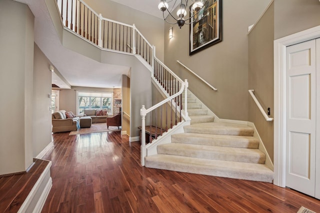 stairway featuring a towering ceiling, a chandelier, and hardwood / wood-style flooring