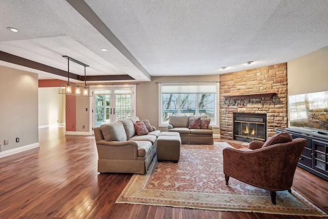 living room featuring dark hardwood / wood-style flooring, a stone fireplace, and a textured ceiling