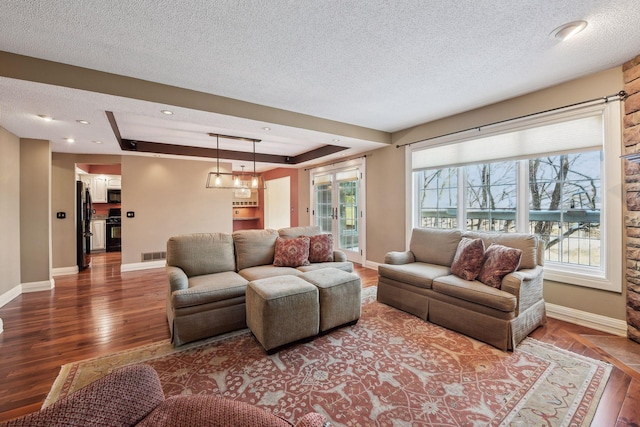 living room featuring wood-type flooring, plenty of natural light, and a textured ceiling