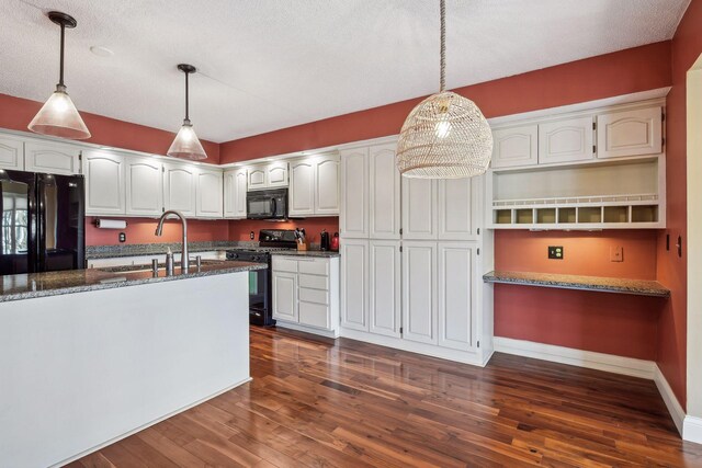 kitchen featuring dark stone countertops, pendant lighting, black appliances, sink, and white cabinets