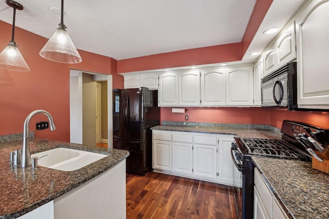 kitchen with white cabinetry, dark stone counters, hanging light fixtures, black appliances, and sink