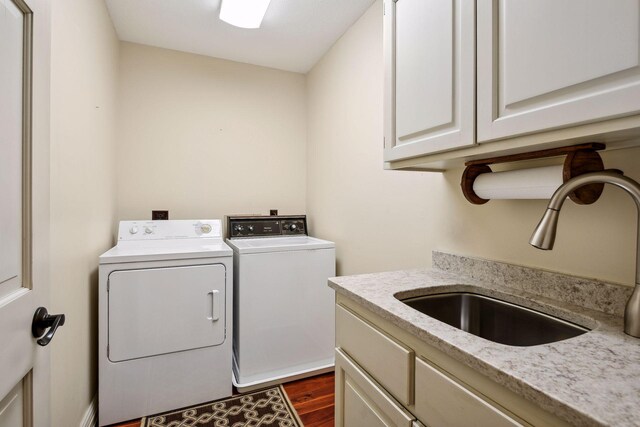 washroom with sink, dark wood-type flooring, washer and dryer, and cabinets