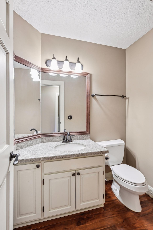 bathroom featuring a textured ceiling, toilet, hardwood / wood-style floors, and vanity