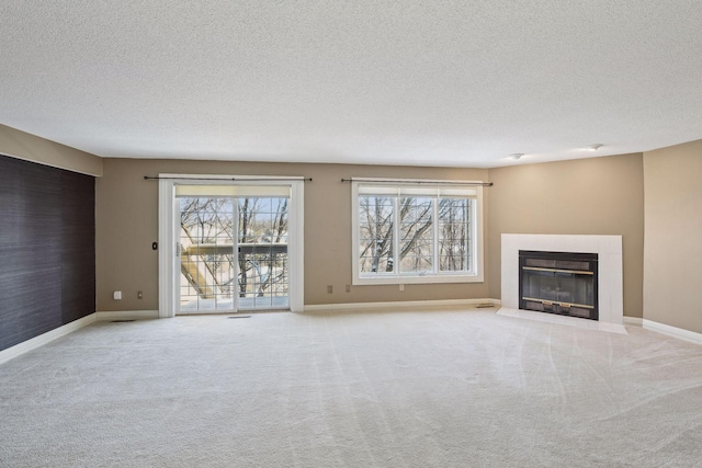 unfurnished living room with light colored carpet, a tile fireplace, and a textured ceiling