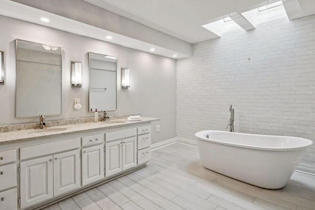 bathroom with vanity, a skylight, and a tub