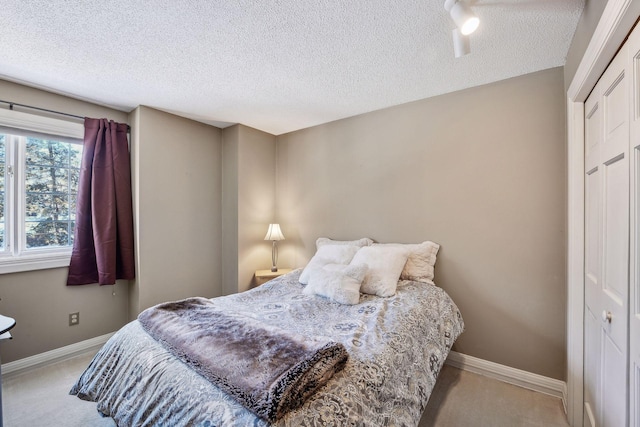 carpeted bedroom featuring a textured ceiling and a closet