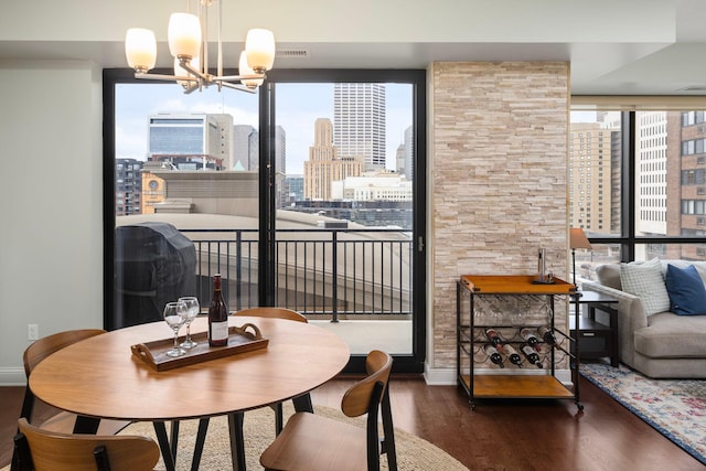 dining room featuring an inviting chandelier, a wealth of natural light, dark wood-style flooring, and a city view