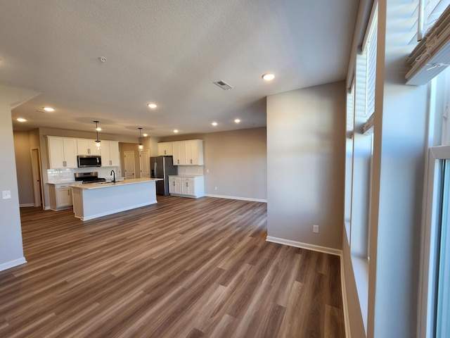 kitchen with a center island with sink, white cabinetry, hanging light fixtures, and appliances with stainless steel finishes