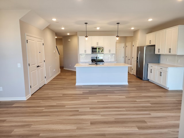 kitchen with white cabinetry, pendant lighting, stainless steel appliances, and light hardwood / wood-style flooring