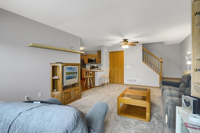 living room with ceiling fan, light colored carpet, and a textured ceiling