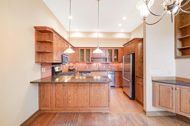 kitchen with sink, hanging light fixtures, tasteful backsplash, kitchen peninsula, and appliances with stainless steel finishes