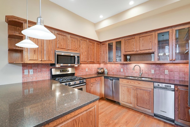 kitchen with pendant lighting, sink, decorative backsplash, dark stone countertops, and appliances with stainless steel finishes