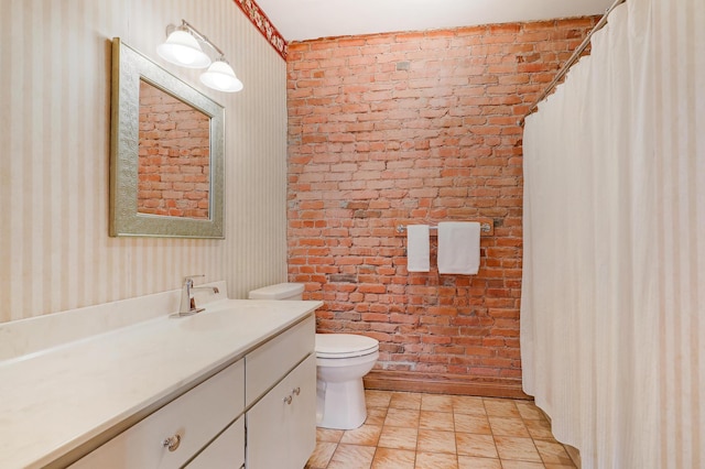 bathroom with vanity, brick wall, and toilet