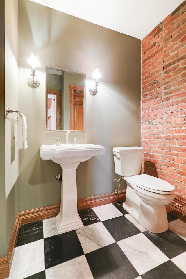 bathroom featuring brick wall and toilet