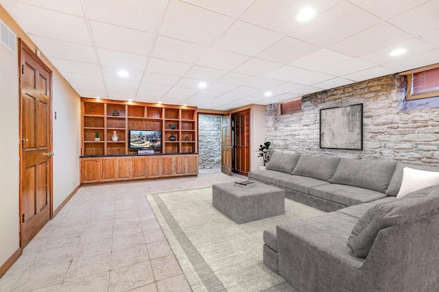 living room featuring a drop ceiling and built in features