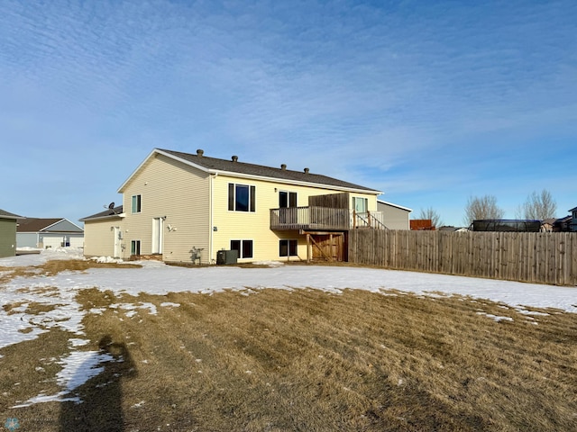 snow covered back of property featuring a lawn, central AC, and a deck