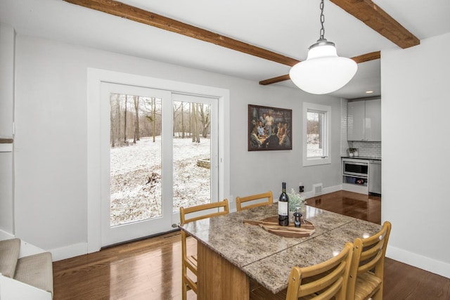 dining room with a wealth of natural light, beamed ceiling, and hardwood / wood-style flooring