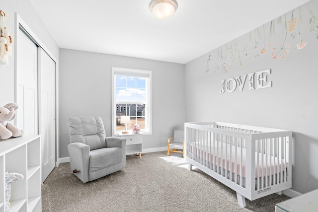 carpeted bedroom with a closet, a crib, and baseboards